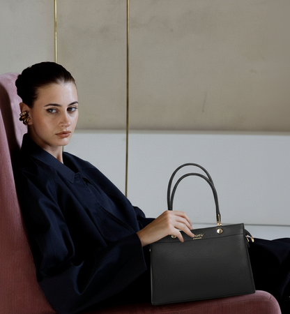 Woman holding a black handbag in an indoor setting