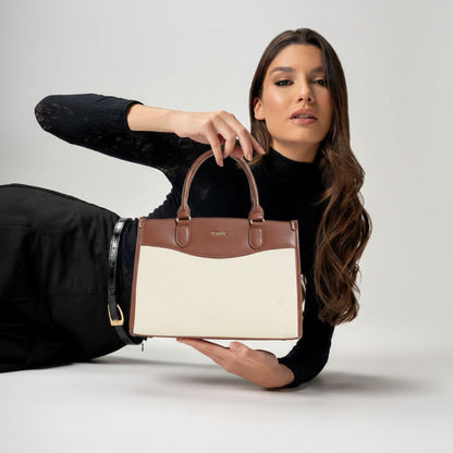 Woman holding a two-toned handbag against a plain background