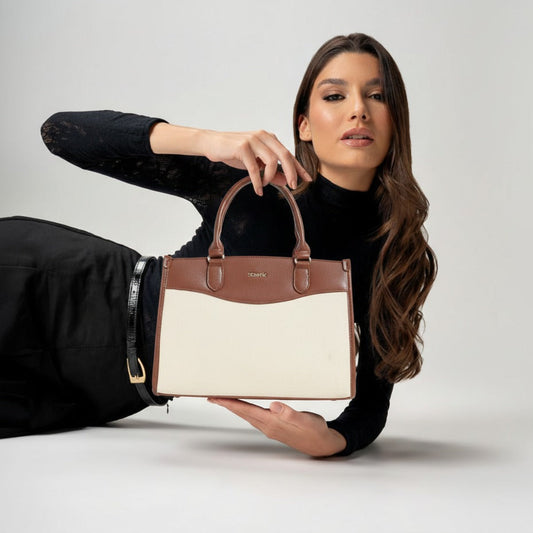 Woman holding a two-toned handbag against a plain background